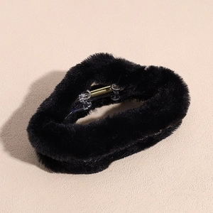Detailed close-up of a black plush faux fur hair claw clip with golden metal spring