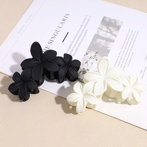 Pinces à cheveux fleurs mates élégantes en noir et blanc crème sur un magazine chic
