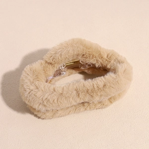 Detail of plush faux fur hair claw clip in light beige with golden metal spring component