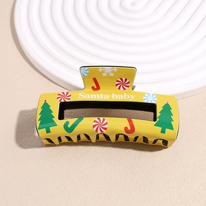 Detail of Christmas hair claw clip with Santa Baby print and festive holiday patterns