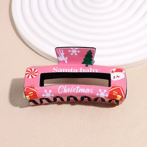 Detail of pink Christmas hair claw clip featuring Santa Baby print and festive patterns