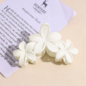 Détail d'une pince à cheveux blanche à trois fleurs avec finition résine mate