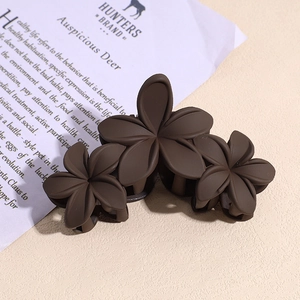 Détail de la pince à cheveux mate café foncé avec un design à trois fleurs élégantes