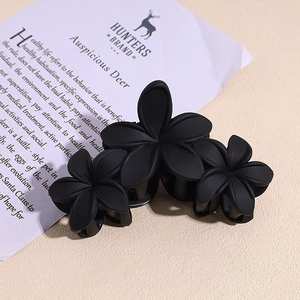 Vue détaillée d'une pince à cheveux mate noire avec design à trois fleurs pour femmes