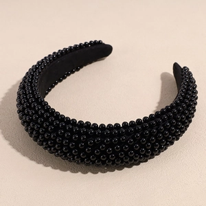 Detail of a thick black padded headband fully covered in glossy black resin beads