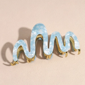 Detail of light blue marble acetate hair claw with wave shape and gold metal teeth