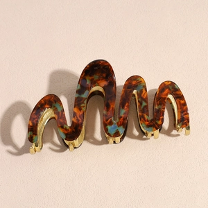Close-up of wavy tortoiseshell acetate hair claw clip with golden metal inner teeth