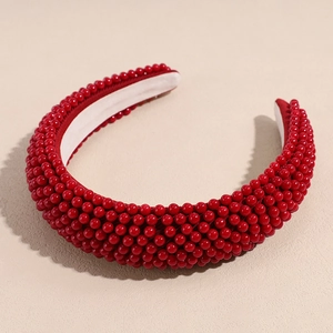 Detail of hand-beaded red sponge headband showing luxury texture and pearl finish