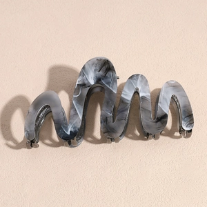 Detail of a wavy acetate shark hair clip with a stylish black and white marble pattern
