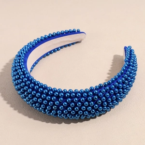 Detailed view of deep blue padded headband with dense faux pearl embellishments