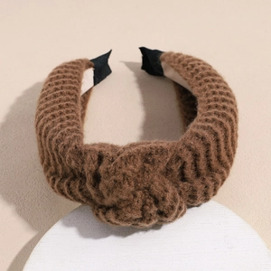 Detail of a brown knitted headband with a cross knot and thick textured weave design