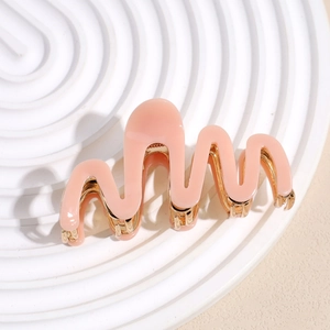 Detail view of pink acetate hair claw clip with golden metal teeth on spiral base