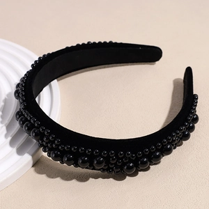 Detailed close-up of a black velvet headband with elegant faux pearl bead embellishments