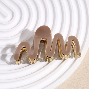 Close-up of stylish wavy acetate shark clip with durable gold metal inner teeth for hair