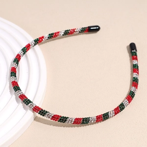 Detail view of festive red and green rhinestone Christmas headband on a stone base