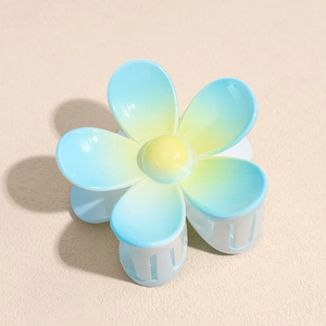 Détail macro d'une pince à cheveux en forme de fleur avec dégradé bleu et jaune vif