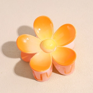 Détail de la pince à cheveux fleur orange avec pétales en résine polie et dents de maintien