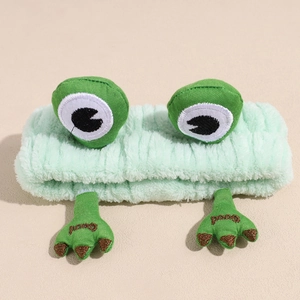 Dettaglio della fascia per capelli a rana verde in peluche con occhi 3D e ricamo