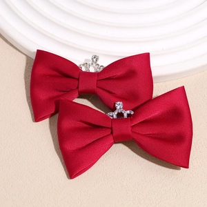 Close-up of deep red velvet bow hair clips featuring crystal crown centerpiece detail