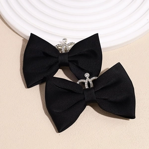 Detail of two black velvet bow hair clips with sparkly rhinestone silver crowns