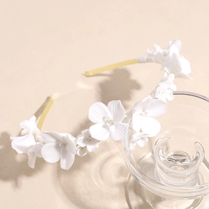 Detailed view of handmade white ceramic flowers and beads on a bridal headband
