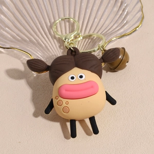 Close-up of cute cartoon doll keychain with golden metal clasp and a small brown bell