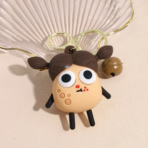 Detailed macro view of a cute cartoon girl keychain with brown pigtails and metal bell