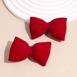 Detail view of two deep red velvet bow hair clips with elegant fiber texture and rich luster