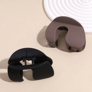 Minimalist matte shark hair clips in black and brown displayed on a ceramic tray