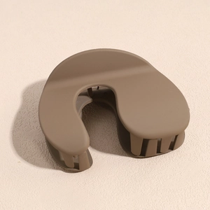Macro detail of matte dark brown hair claw clip with smooth U-shaped streamlined design