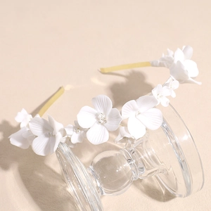 Elegant bridal headband with white ceramic flowers on gold frame for wedding hair styling