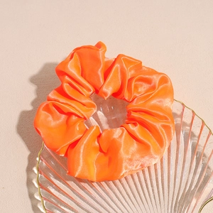 Dettaglio di un elastico per capelli in raso arancione LED su vassoio di vetro
