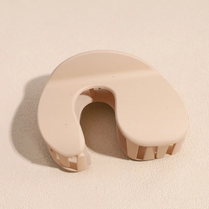 Close-up of matte beige U-shaped shark hair claw clip with minimalist frosted finish