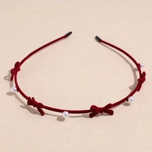 Detail of red velvet headband featuring bow ties and white pearls for a vintage look