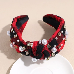 Detail of red plaid headband with white pearls and rhinestones on a white plate