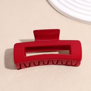 Détail macro d'une pince à cheveux rectangulaire rouge brillant au design ajouré brillant