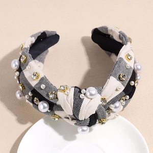 Close-up of knotted headband with black and white plaid, pearls, and golden rhinestones