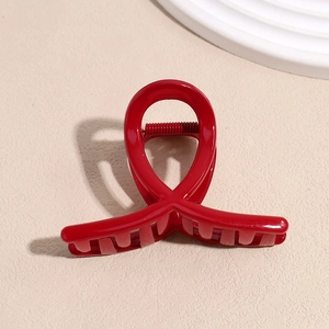 Détail d'une pince à cheveux rouge brillant avec un design élégant à cercles croisés