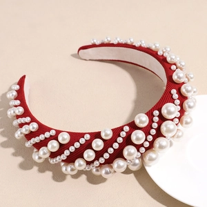 Detail of red sponge headband featuring elegant white faux pearls on textured fabric