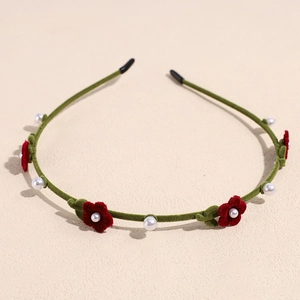 Detail of green flocked headband with red floral accents and white imitation pearls