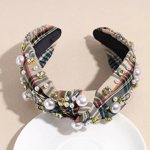 Close-up of beige plaid headband with scattered pearls and shimmering gold-rimmed rhinestones