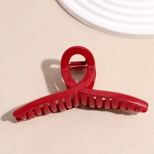 Détail macro d'une pince à cheveux rouge brillant avec structure en boucle croisée