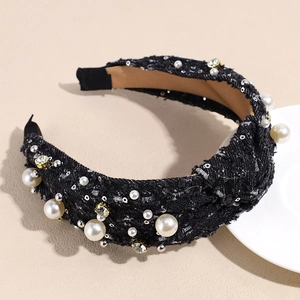 Detail of tweed headband with pearls and rhinestones on a warm beige background