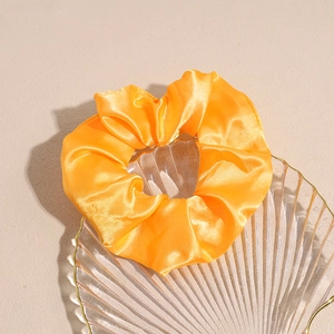 Dettaglio ravvicinato di un elastico per capelli in raso arancione in un piatto