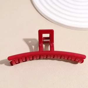 Détail d'une pince à cheveux de mariée rouge en acrylique brillant sur fond beige