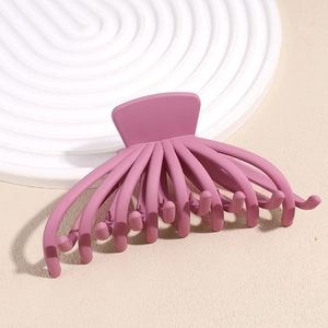 Detail of matte octopus hair claw clip in dusty pink on a white decorative tray