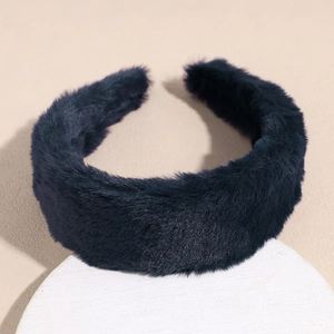 Close-up of a wide navy blue plush headband on a white pedestal for winter hair styling