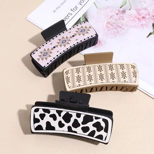 Three large vintage PU leather hair claw clips with geometric and cow print patterns