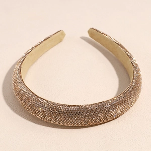 Détail d'un serre-tête rembourré doré champagne orné d'un sertissage dense de strass brillants