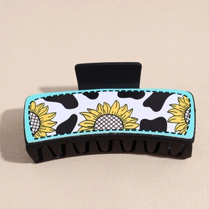Detail of square hair claw clip featuring cow print and sunflower pattern on matte finish